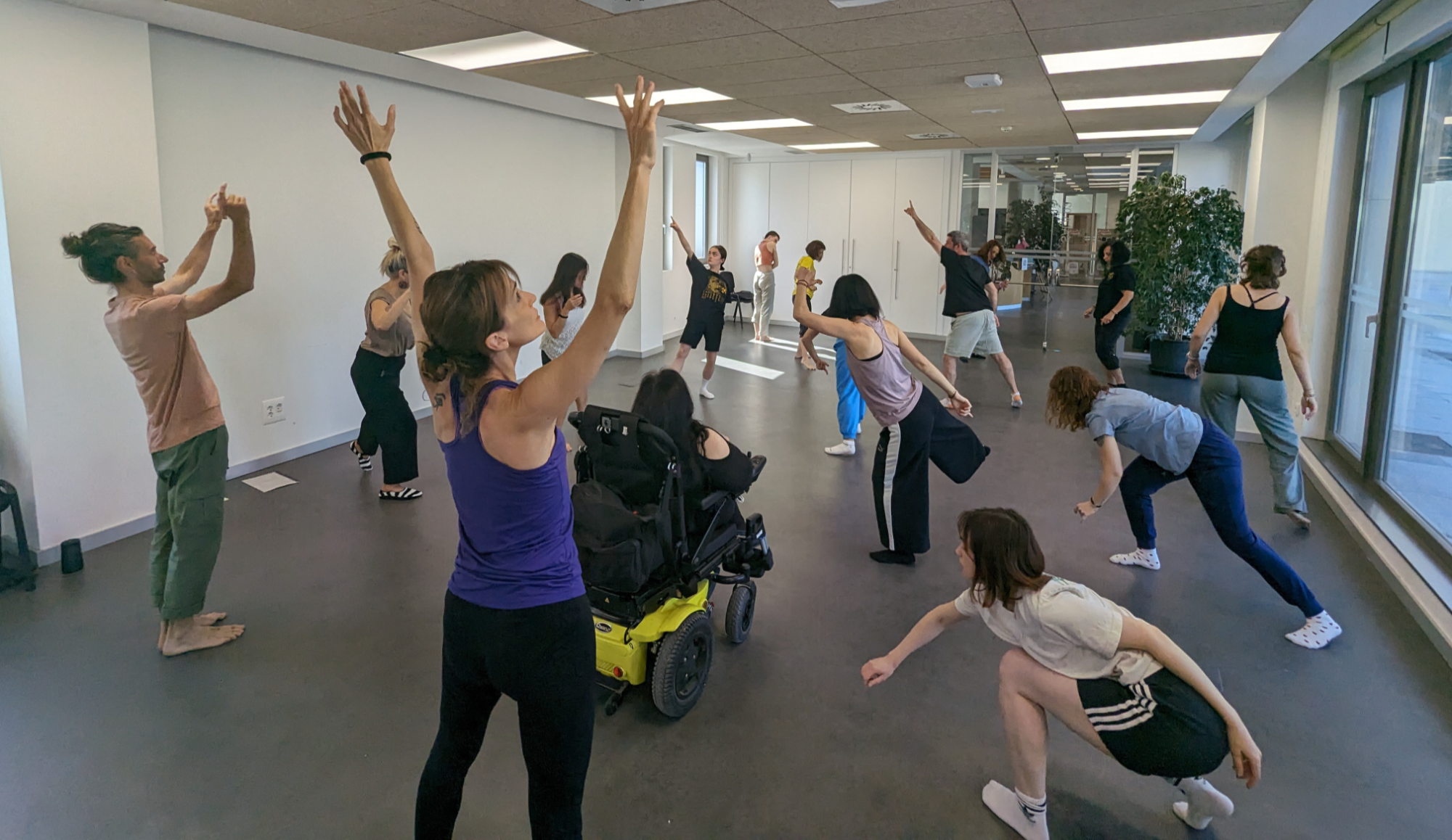 Inclusive contemporary dance class in Spain with Deaf and hearing participants, including a wheelchair user, moving together in a grassroots arts program