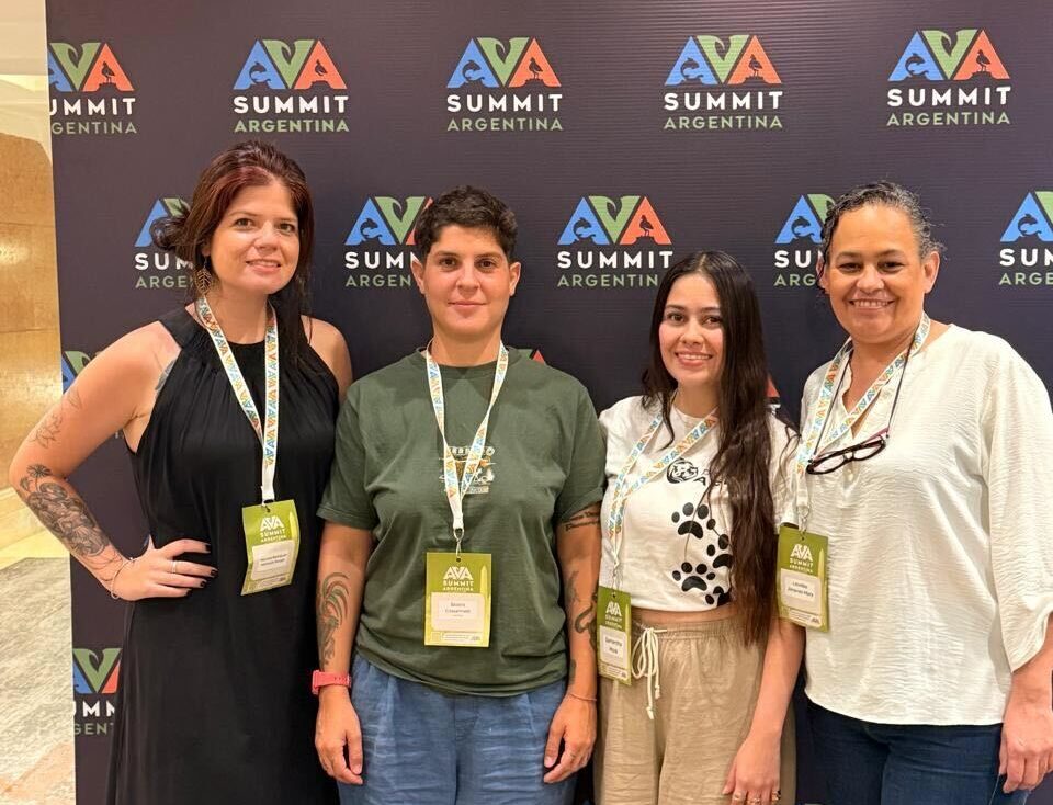 Four young women posing for a photo in front of AVA Argentina panel