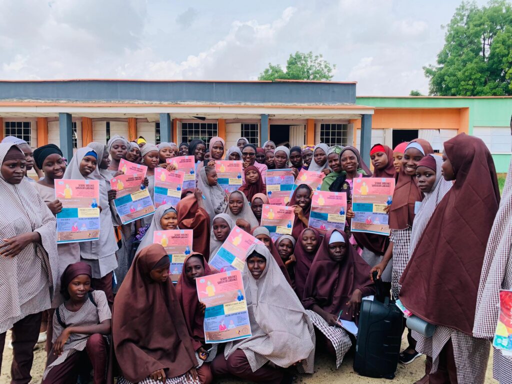 A group photo of young school girls holding the Survivor Guide flyer