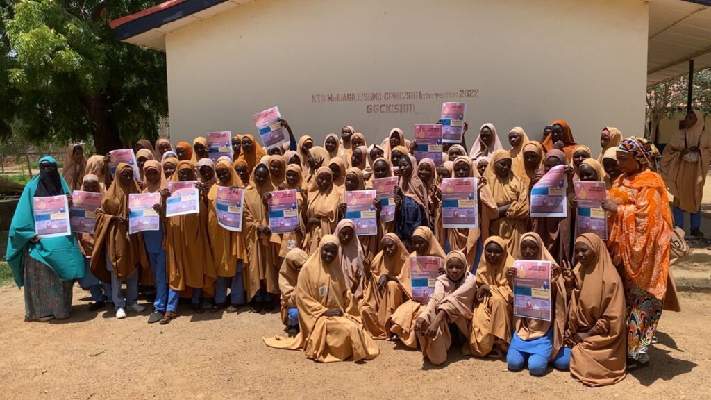 A group photo of young school girls holding the Survivor Guide flyer