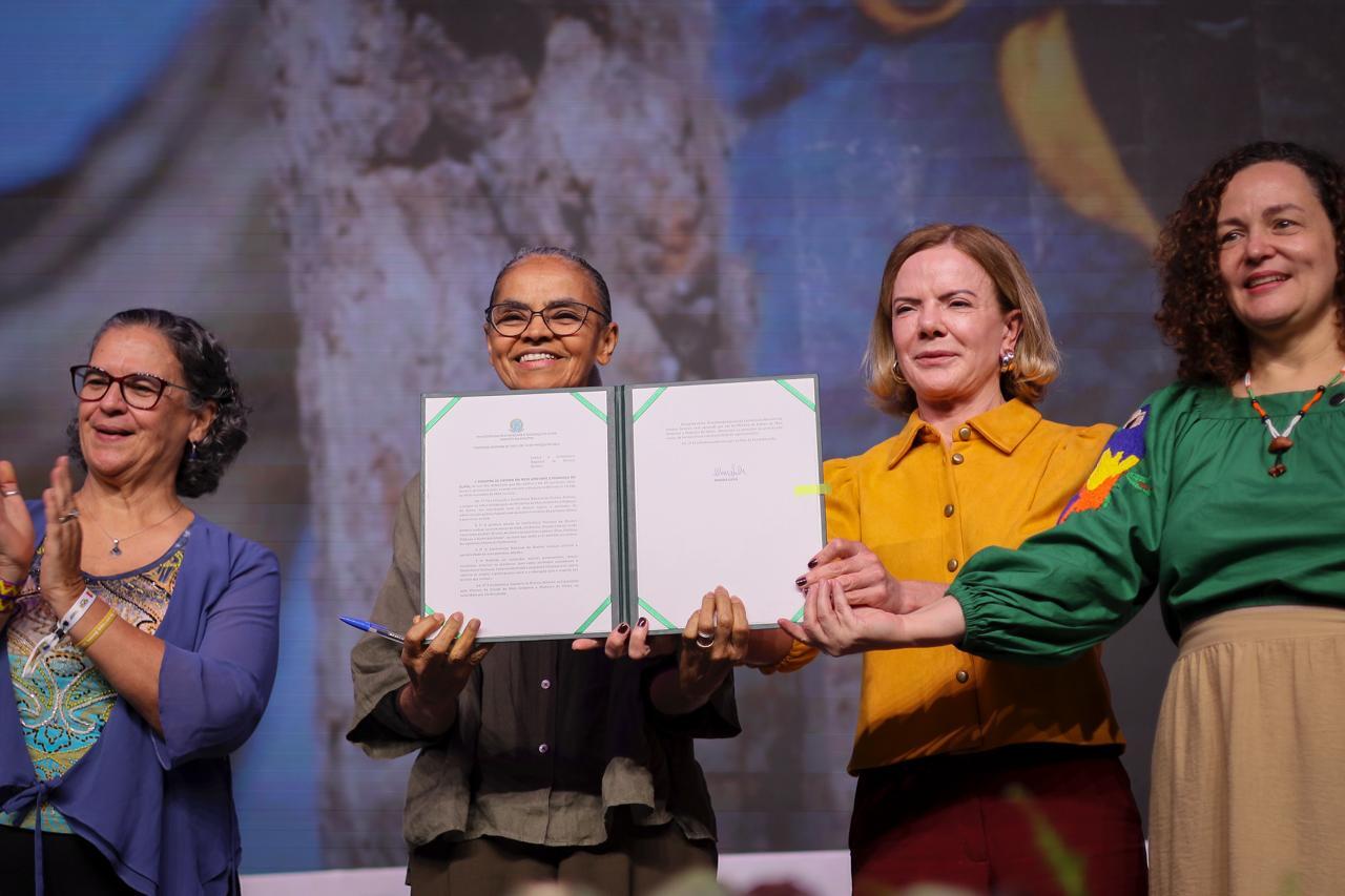 An artist in front a mural with arms open